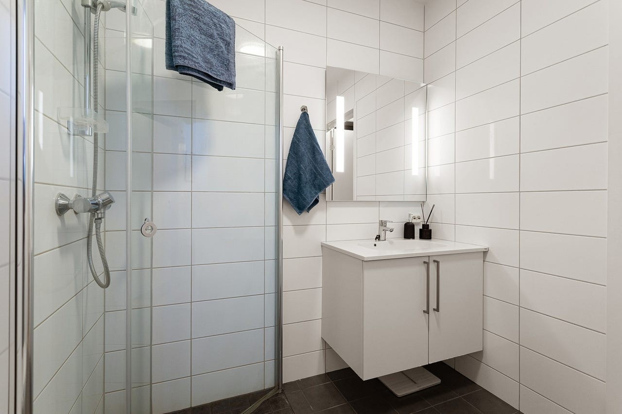 Baderomsinnredning med heldekkende servant og speil med integrert belysning. Galleribilde