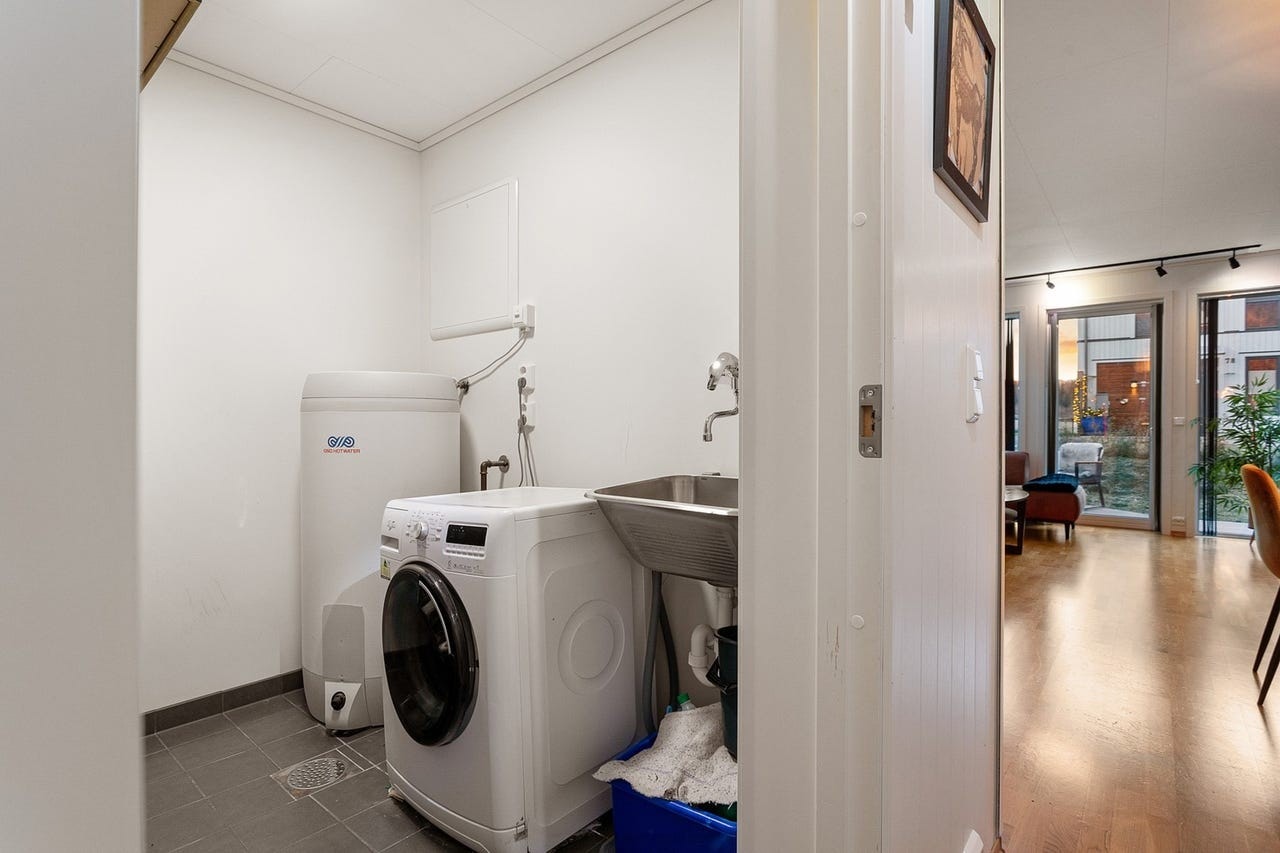 Praktisk vaskerom med flislagt gulv med varme, utslagsvask og opplegg for vaskemaskin. Galleribilde