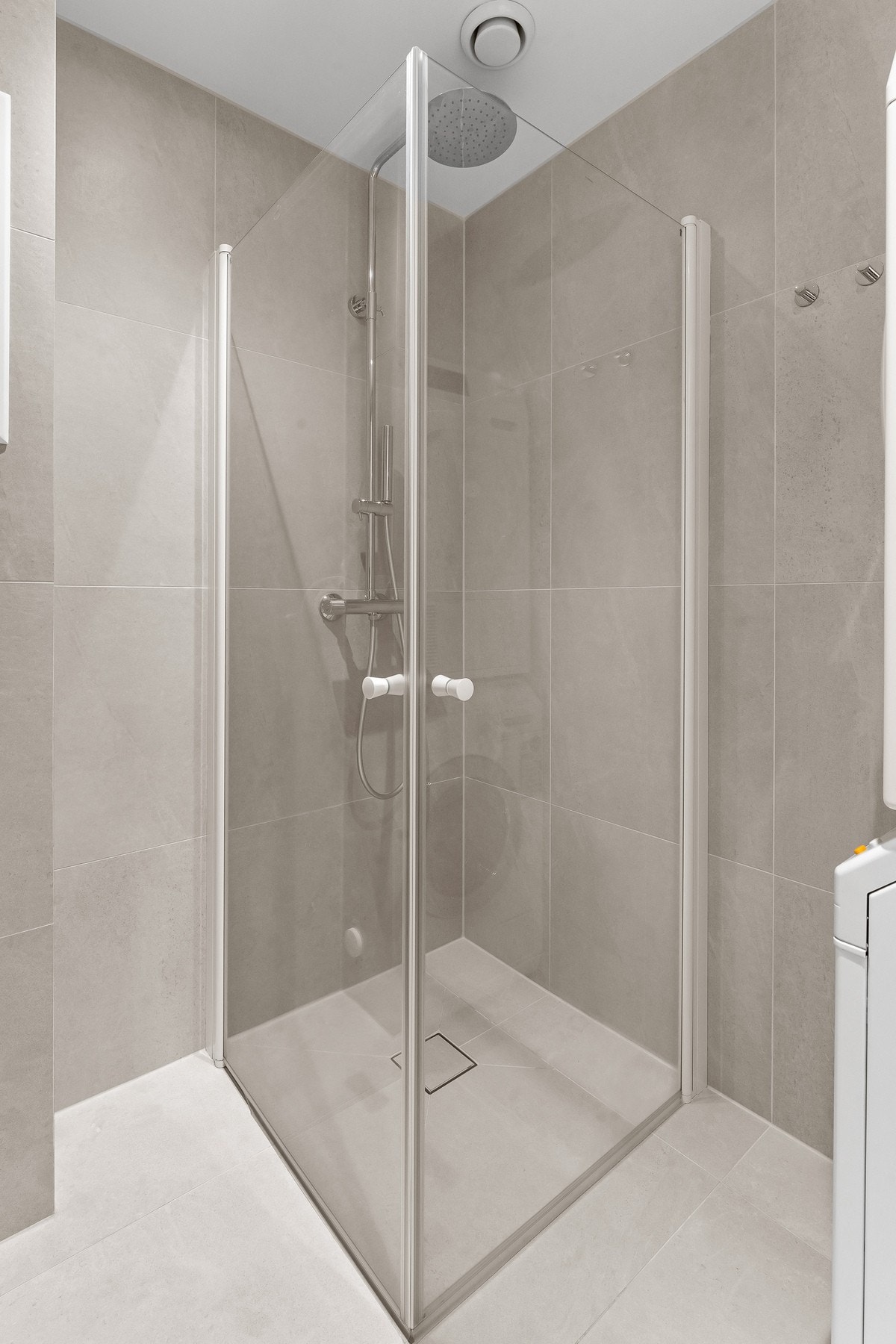 Badet er innredet med vegghengt toalett, servantinnredning med heldekkende servant, speilskap og dusjhjørne med glassdører. Galleribilde