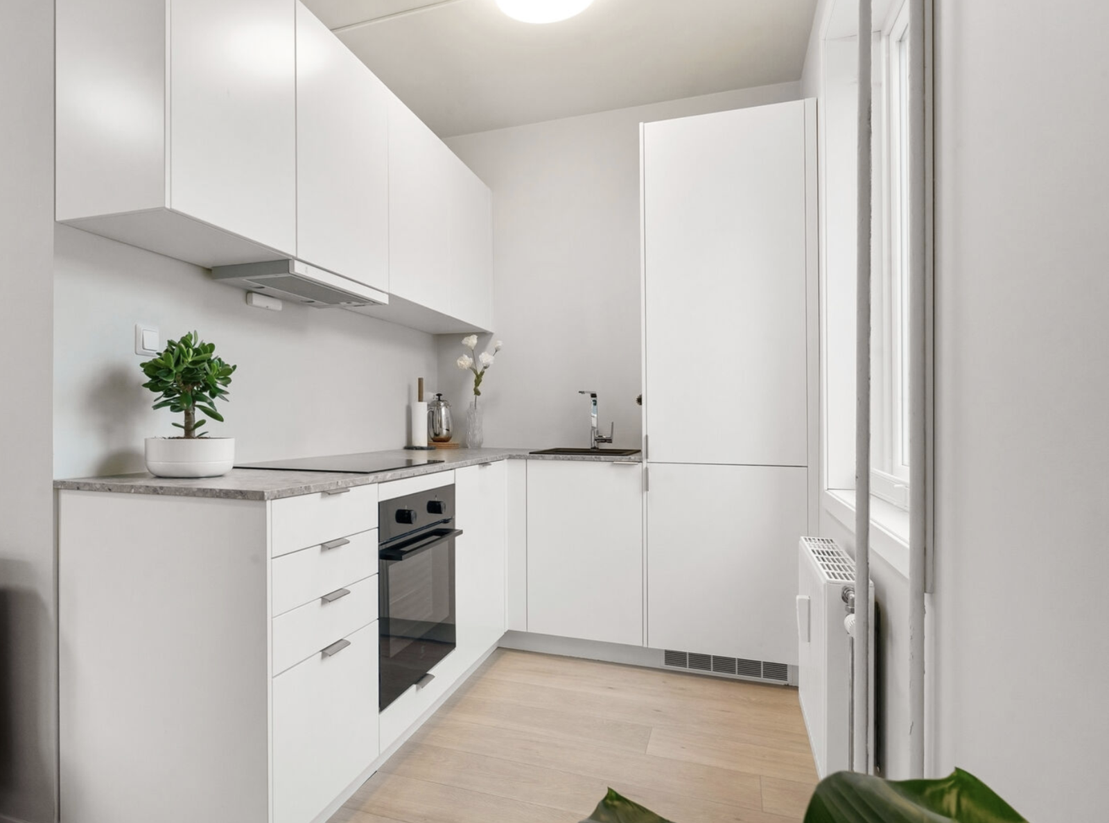 Glatt kjøkkeninnredning med benkeplate i laminat og integrerte hvitevarer. Galleribilde
