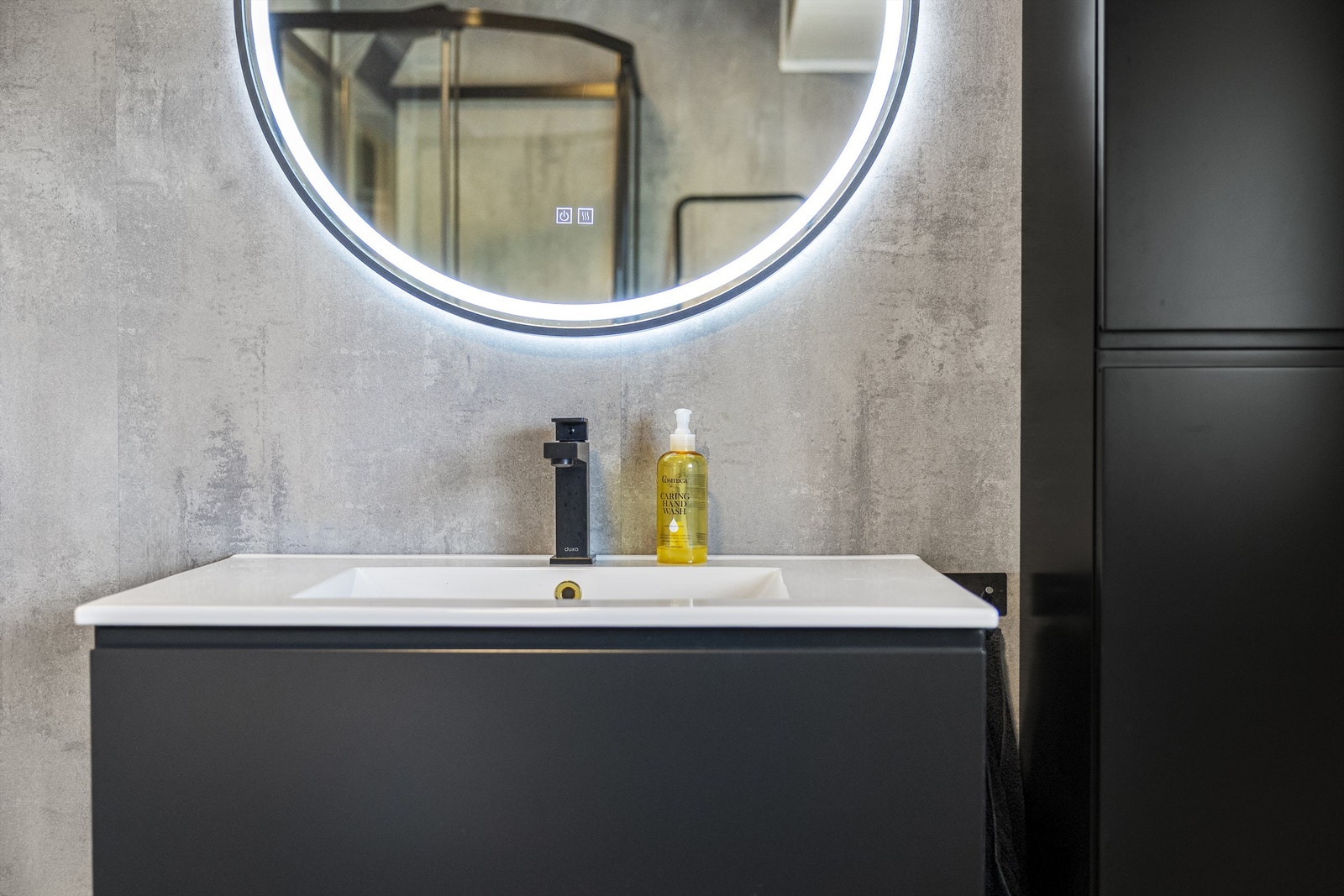 Badet har baderomsplater på veggene og en moderne, mørk innredning. Galleribilde