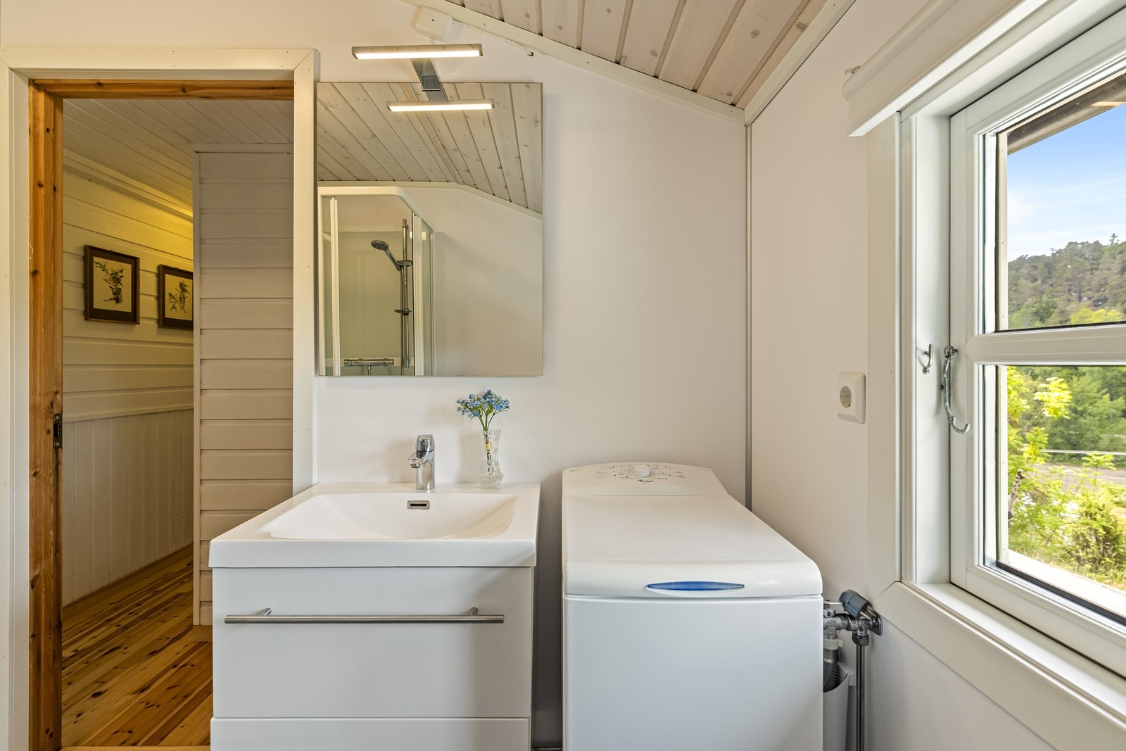 Praktisk innredet bad med heldekkende servant, speil med overlys og opplegg for vaskemaskin. Galleribilde