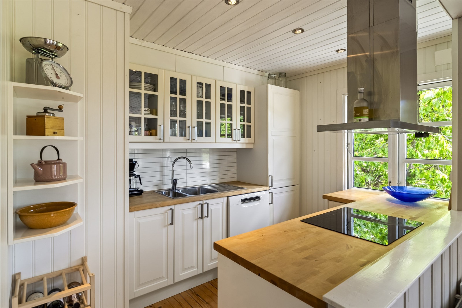 Kjøkkenet ligger i delvis åpen løsning mot stuen og har lys innredning med profilerte fronter og benkeplate i tre. Det er montert Kitchen Board-plater mellom benkeplate og overskap. Galleribilde