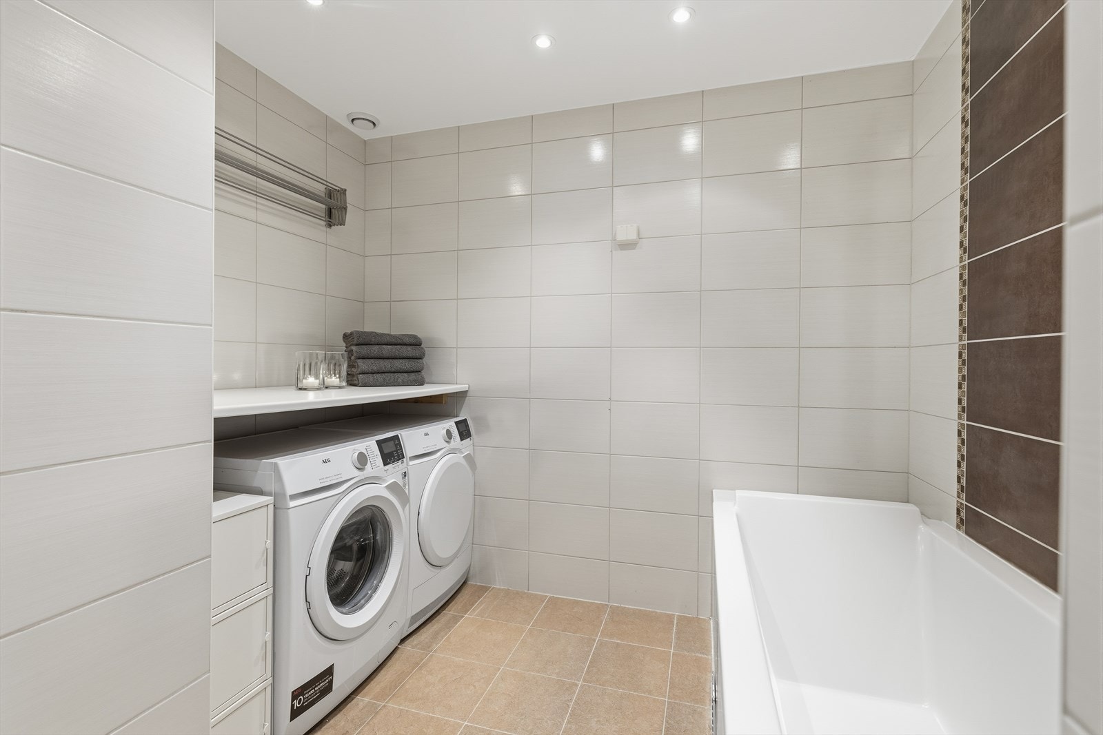 Badet har opplegg for vaskemaskin og tørketrommel, med en praktisk brettebenk over. Galleribilde