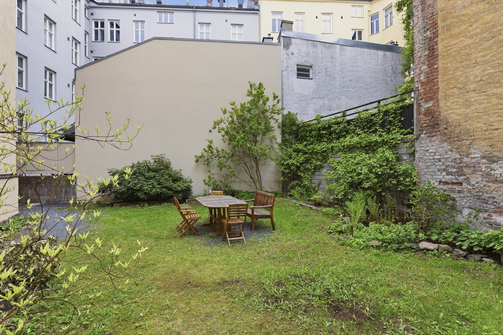 Bakgården er pent beplantet med busker og trær. Galleribilde