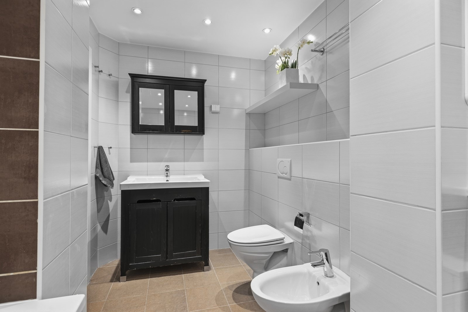 Baderomsinnredning med heldekkende servant og underskap, samt speilskap. Vegghengt wc og bidet. Rommet har mekanisk avtrekk. Galleribilde