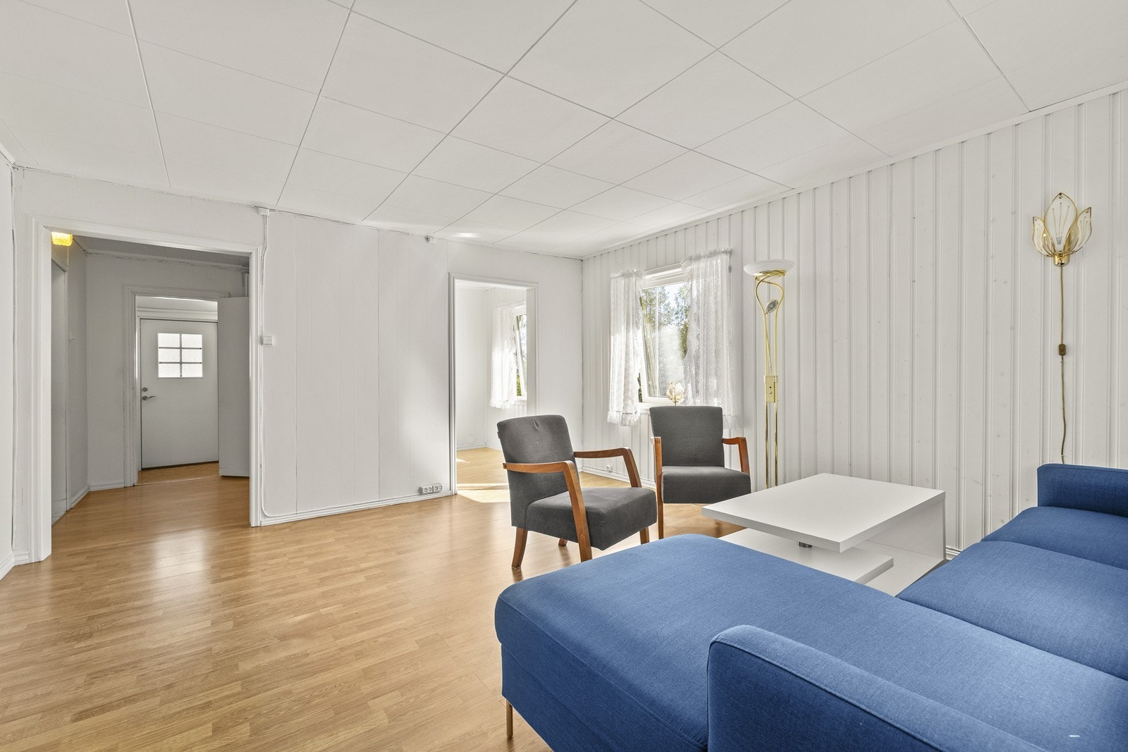 Gjennomgående laminatgulv og malte trepanel på veggene skaper en helhetlig stil. Galleribilde