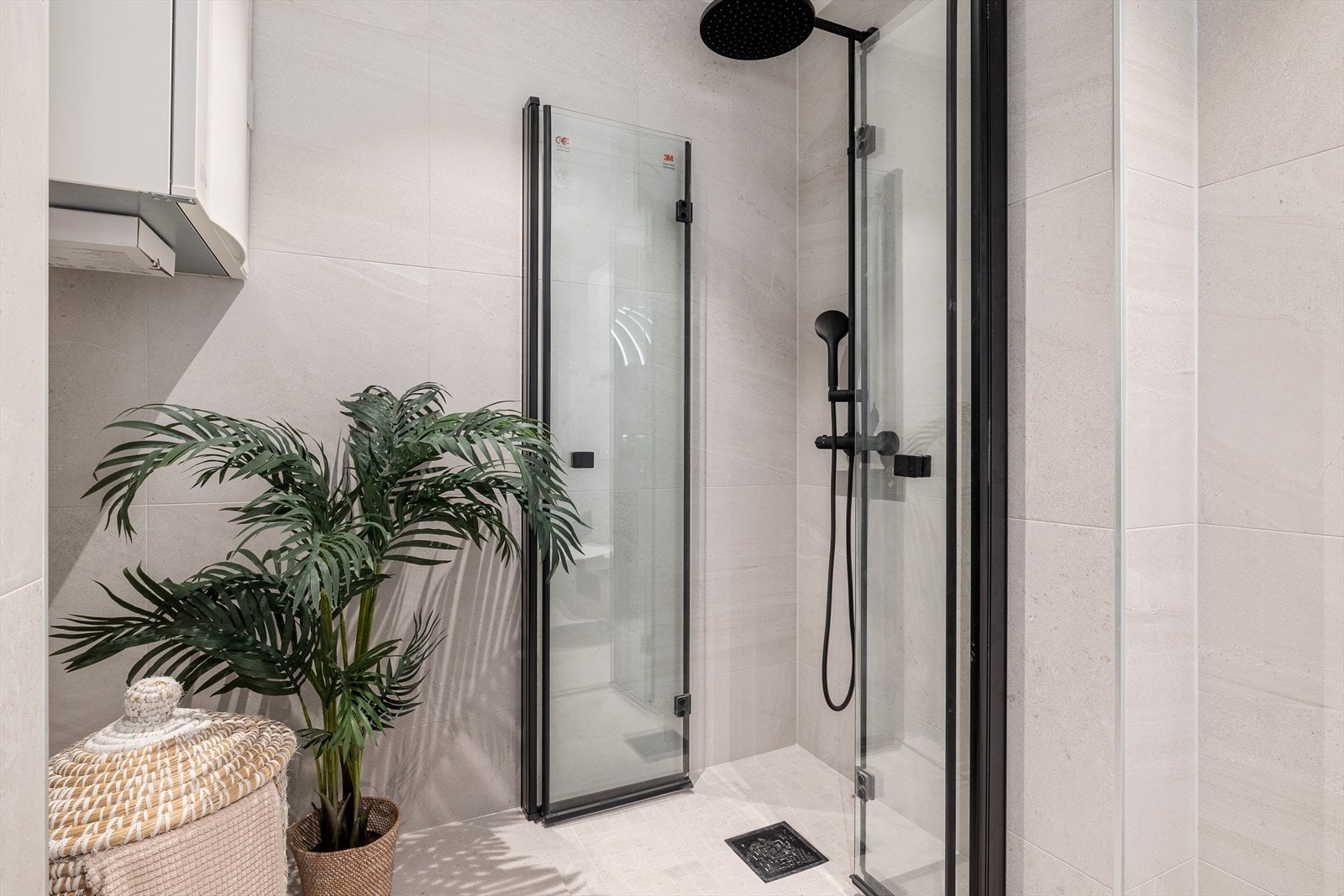 Badet inneholder vegghengt toalett, helstøpt servant med skuffer under, dusjdører i klart glass og opplegg for vaskemaskin. Galleribilde