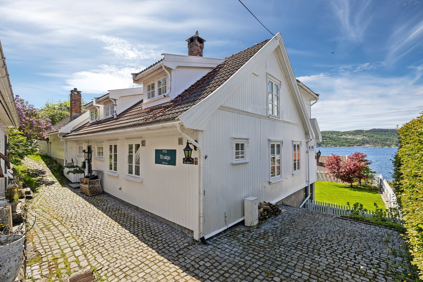 Eiendommen har en sjarmerende, brosteinsbelagt adkomst og en pent opparbeidet tomt som er inngjerdet med stakittgjerde. Galleribilde