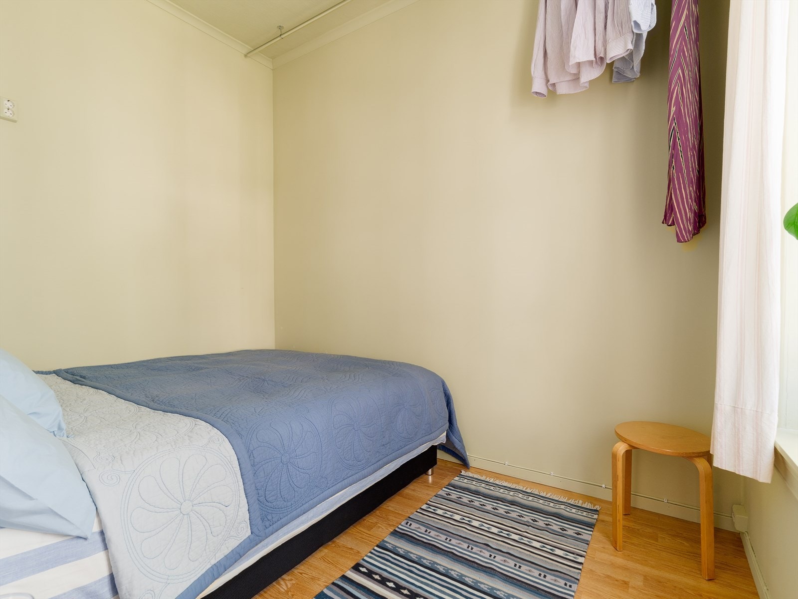 Det er satt opp en praktisk garderobestang som strekker seg gjennom den ene veggen på soverommet, noe som bidrar til både oppbevaringsplass og et fint pynteelement. Galleribilde