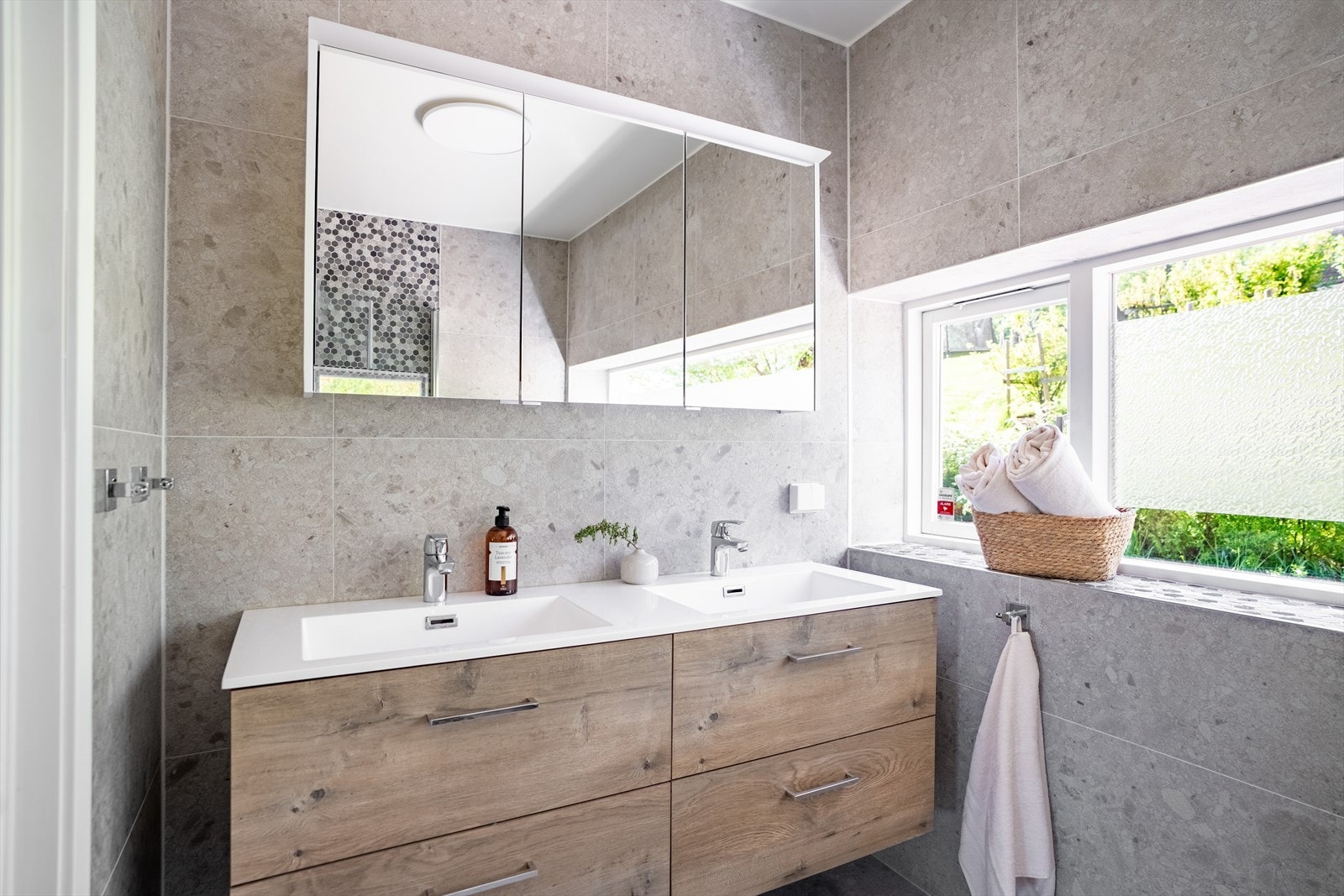 Badet i hovedetasjen fremstår delikat med moderne innredning og store flisflater. Godt lysinnslipp og doble servanter gir rommet et eksklusivt preg. Galleribilde