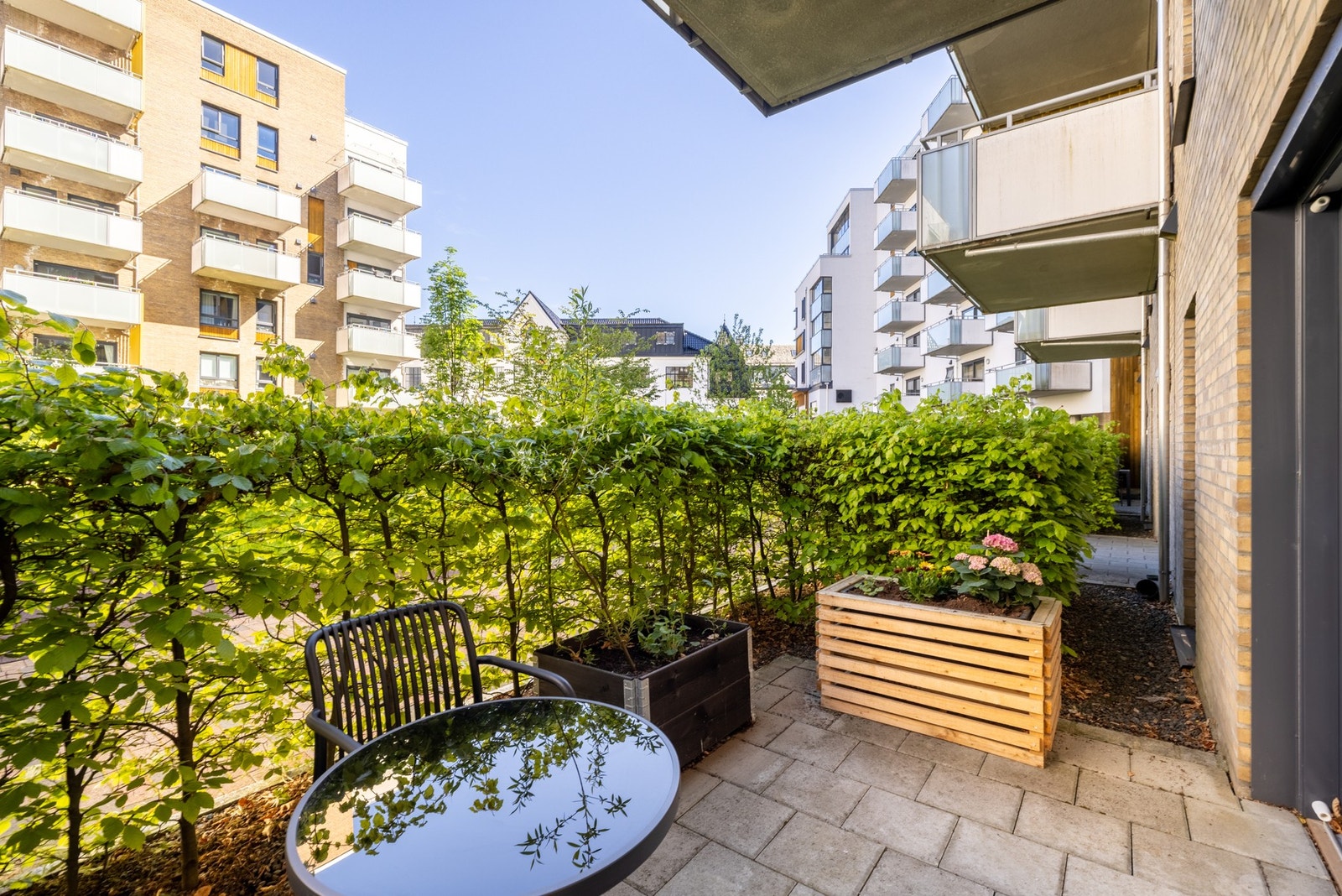 Leiligheten har en herlig terrasse som er pent rammet inn og skjermet med en hekk. Galleribilde