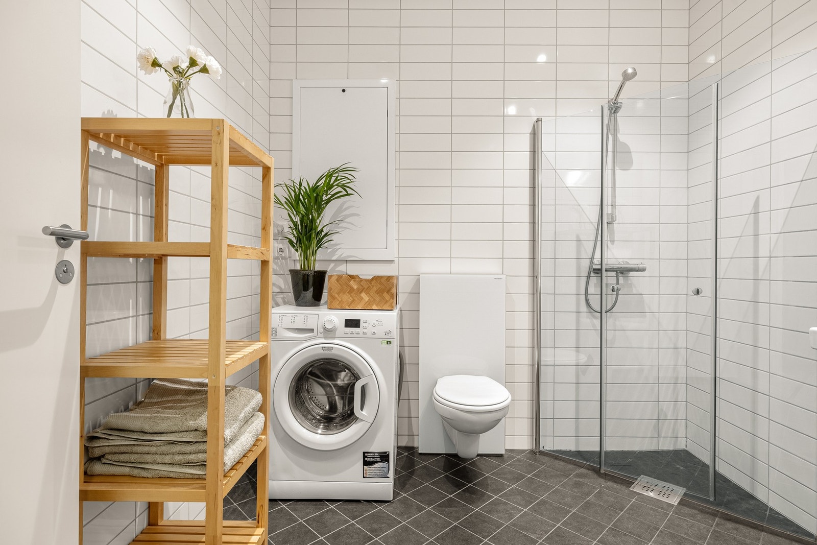 Badet er innredet med veggehengt toalett, dusjhjørne med glassvegger, og baderomsmøblement med speil og belysning. Galleribilde