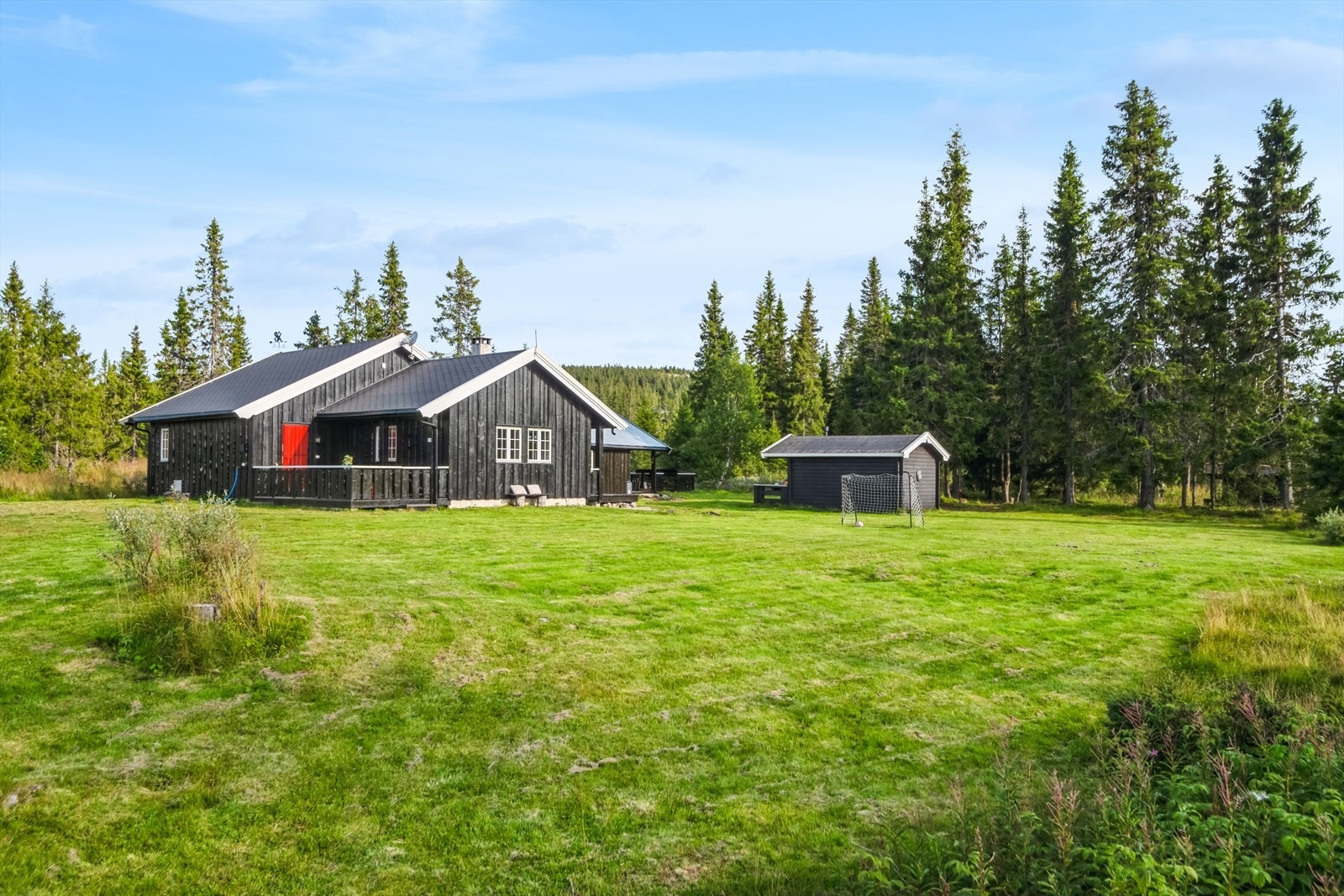 Fritidsboligen har terrasse mot sør, med konstruksjoner i treverk, og en opparbeidet tomt med plen og beplantning. Galleribilde