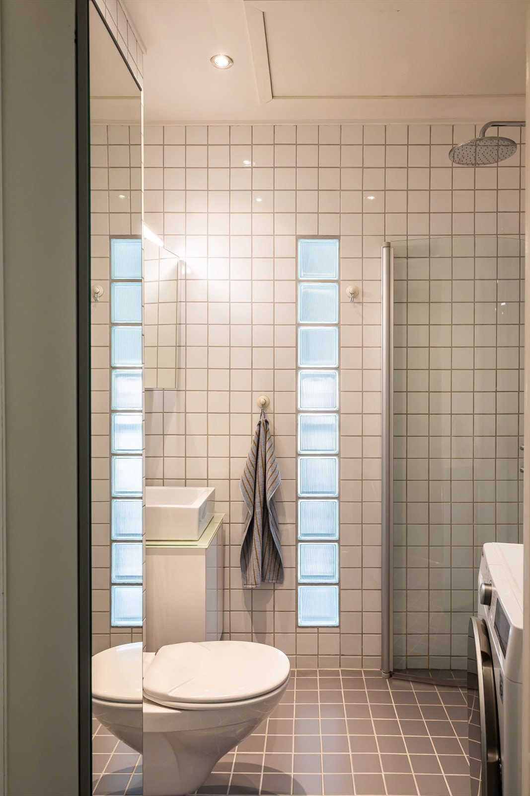 Badet er flislagt og utstyrt med vegghengt toalett og servant. Galleribilde