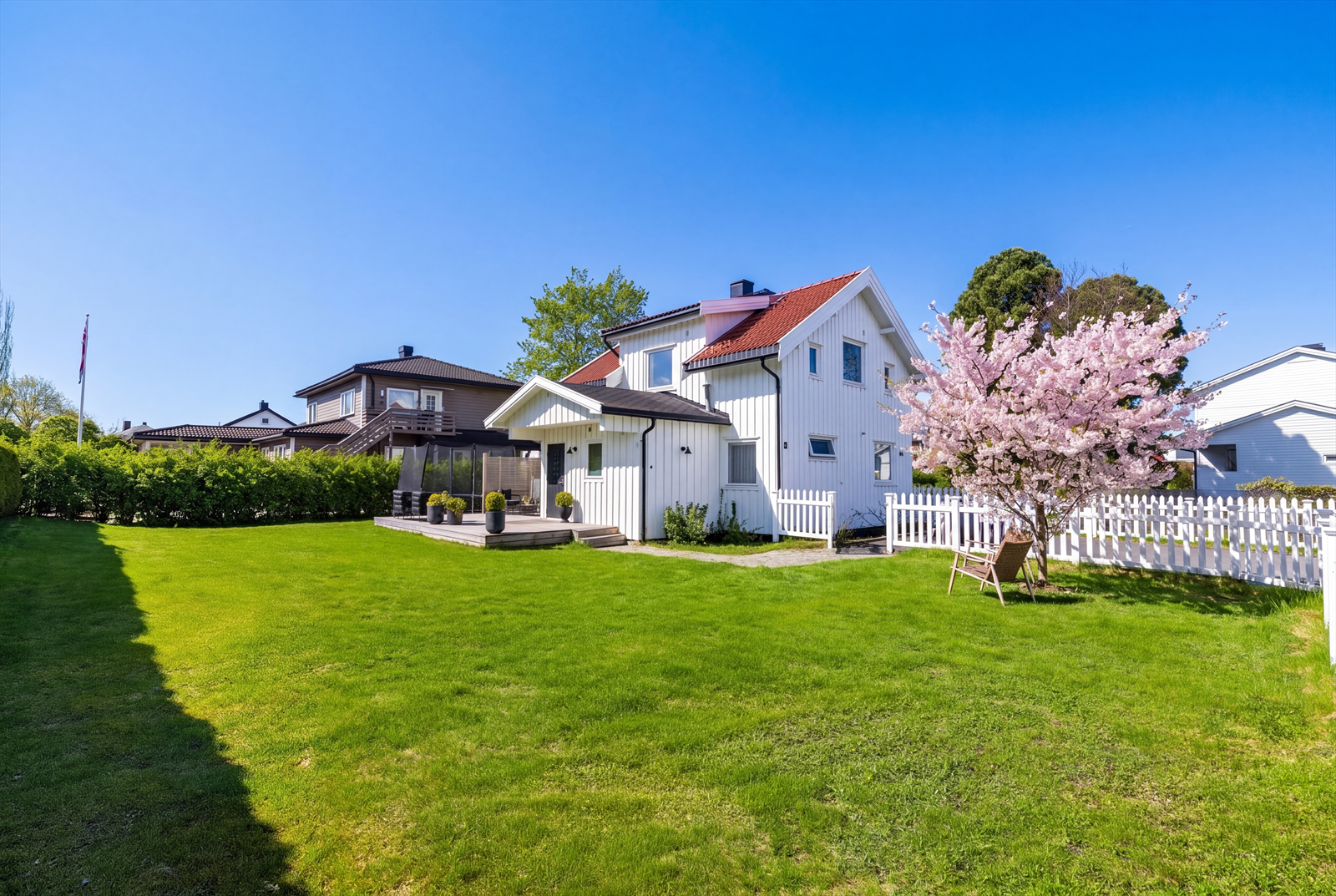 Flat og lettstelt hage av god størrelse, utebod fra 2022 og platting på 31 kvm. (Bildet er AI-redigert med gress og blomstring av treet, avvik kan forekomme) Galleribilde