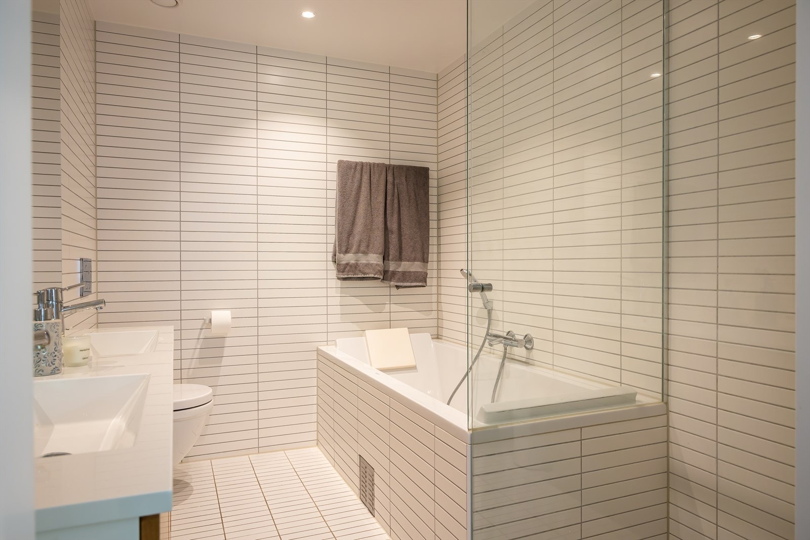 En-suite badet er utstyrt med badekar med dusj, dusjnisje, toalett og servant i helstøpt plate med 2 blandebatterier Galleribilde