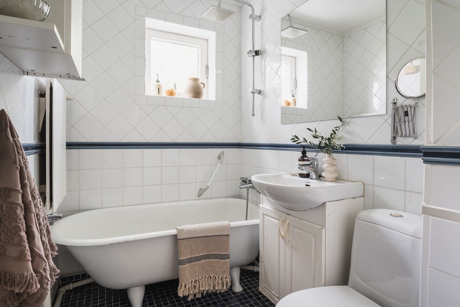 Flislagt bad utstyrt med frittstående badekar og opplegg for vaskemaskin. Galleribilde