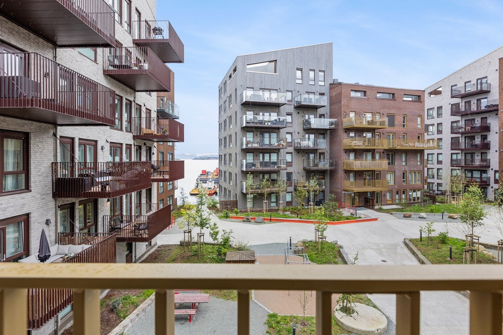 Fra balkongen kan du se sjøen og har oversikt over sameiets velstelte fellesarealer med sitteplasser, lekeplass og grøntområder for beboerne. Galleribilde