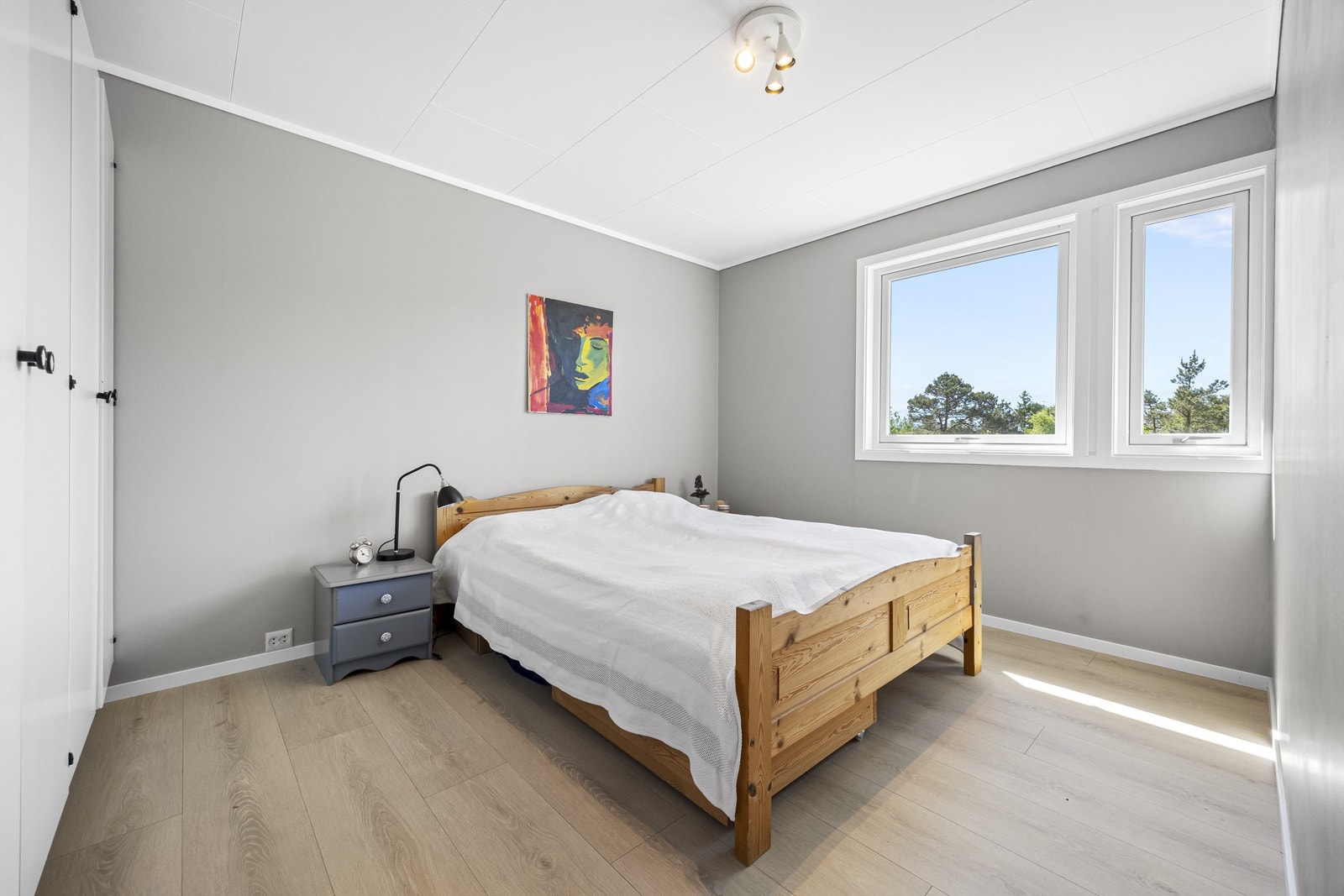 Ett av to soverom i første etasje, med laminat på gulvet og plass til garderobeløsning. Galleribilde