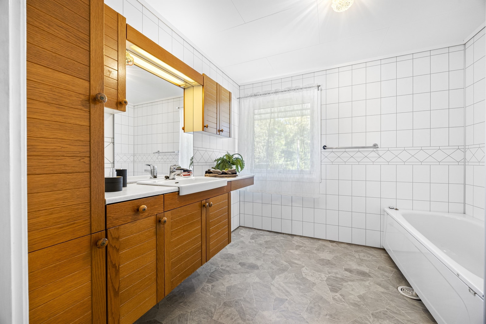 Baderomsinnredning med vegghengt servantskap og speil med overlys. Galleribilde