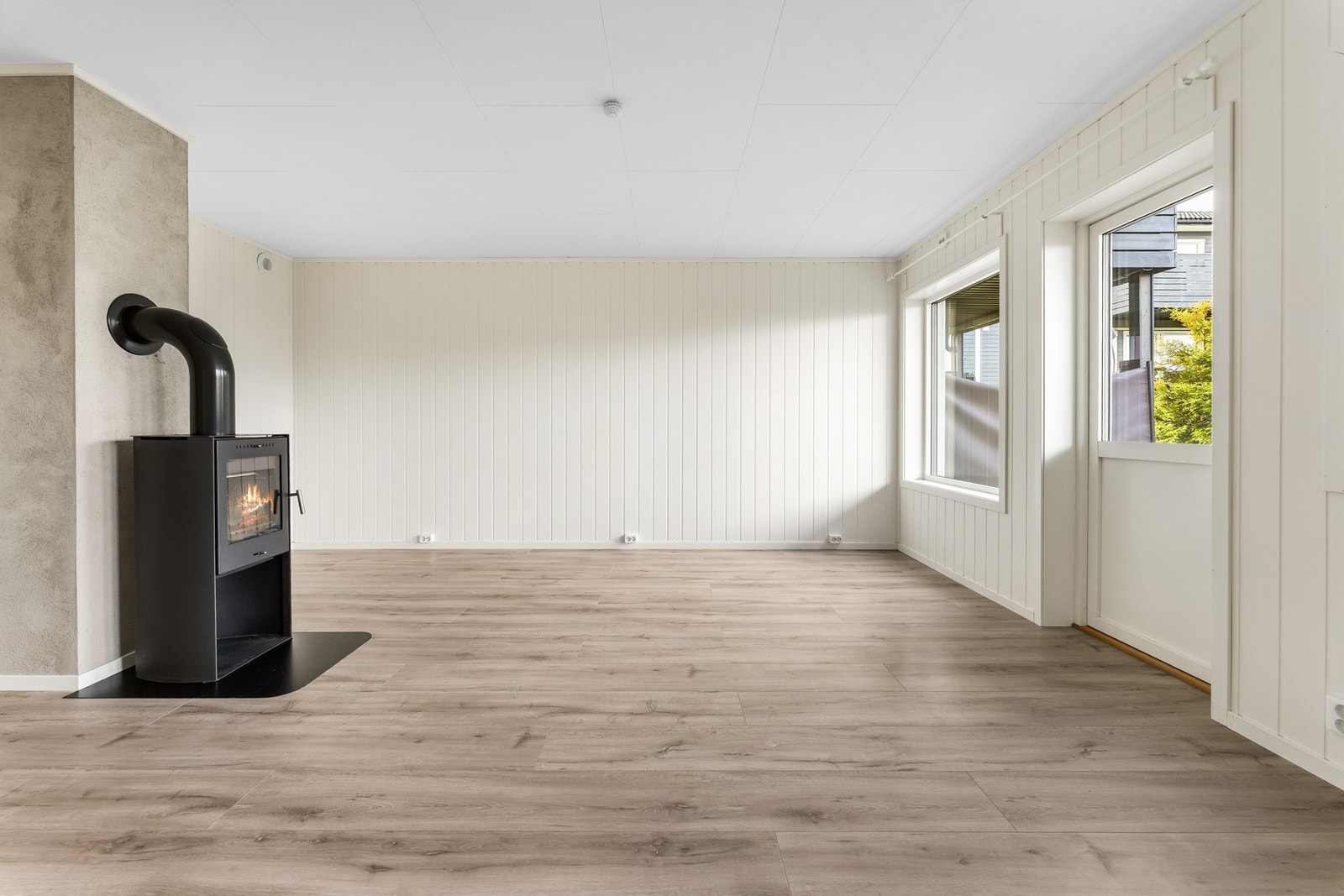 Lys og luftig stue med laminat på gulv og malt panel på vegger. Galleribilde