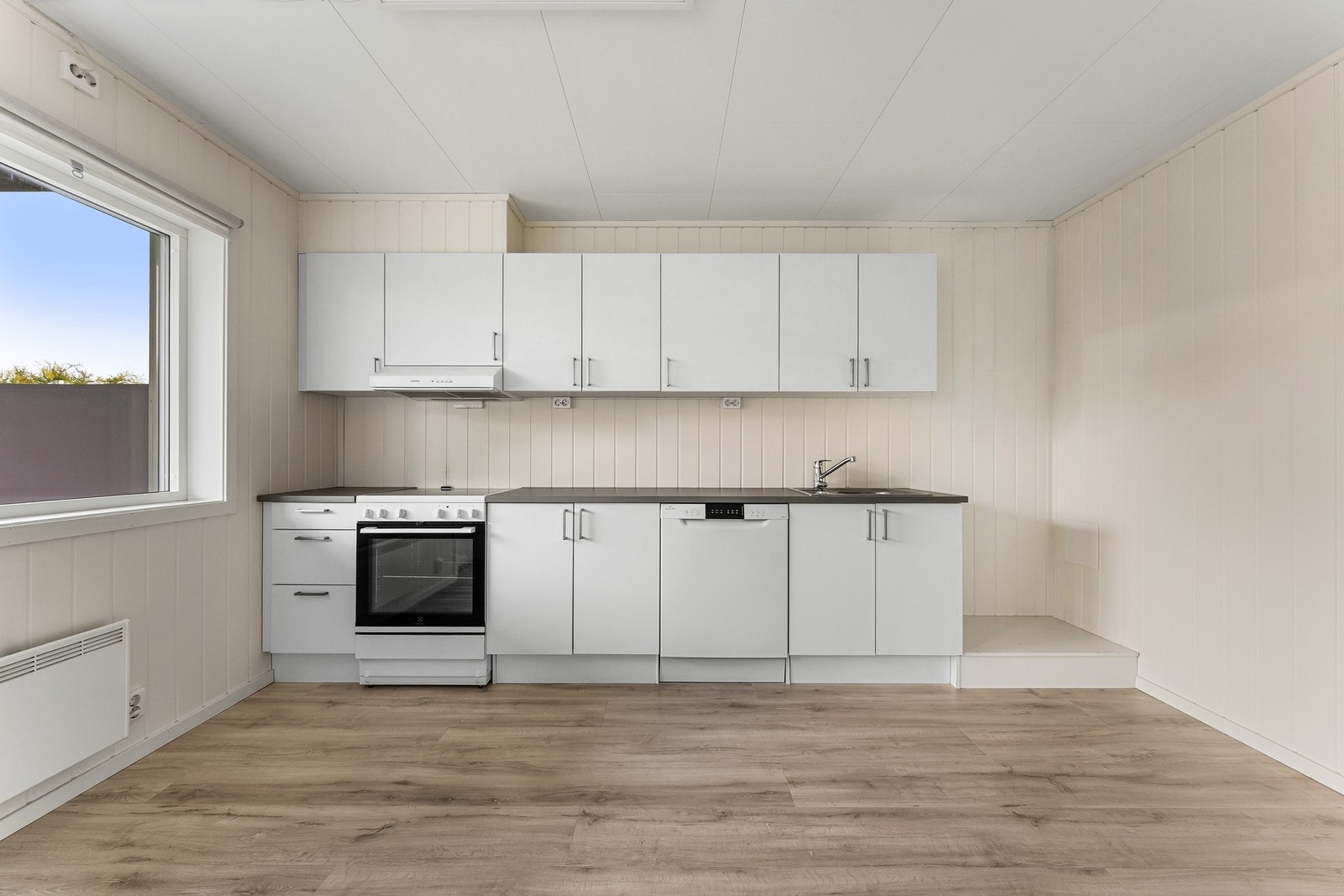 Stilrent kjøkken med hvite glatte fronter og laminat benkeplate med nedfelt vaskekum. Hvitevarer medfølger. Avsatt plass til kjøl/frys. Galleribilde