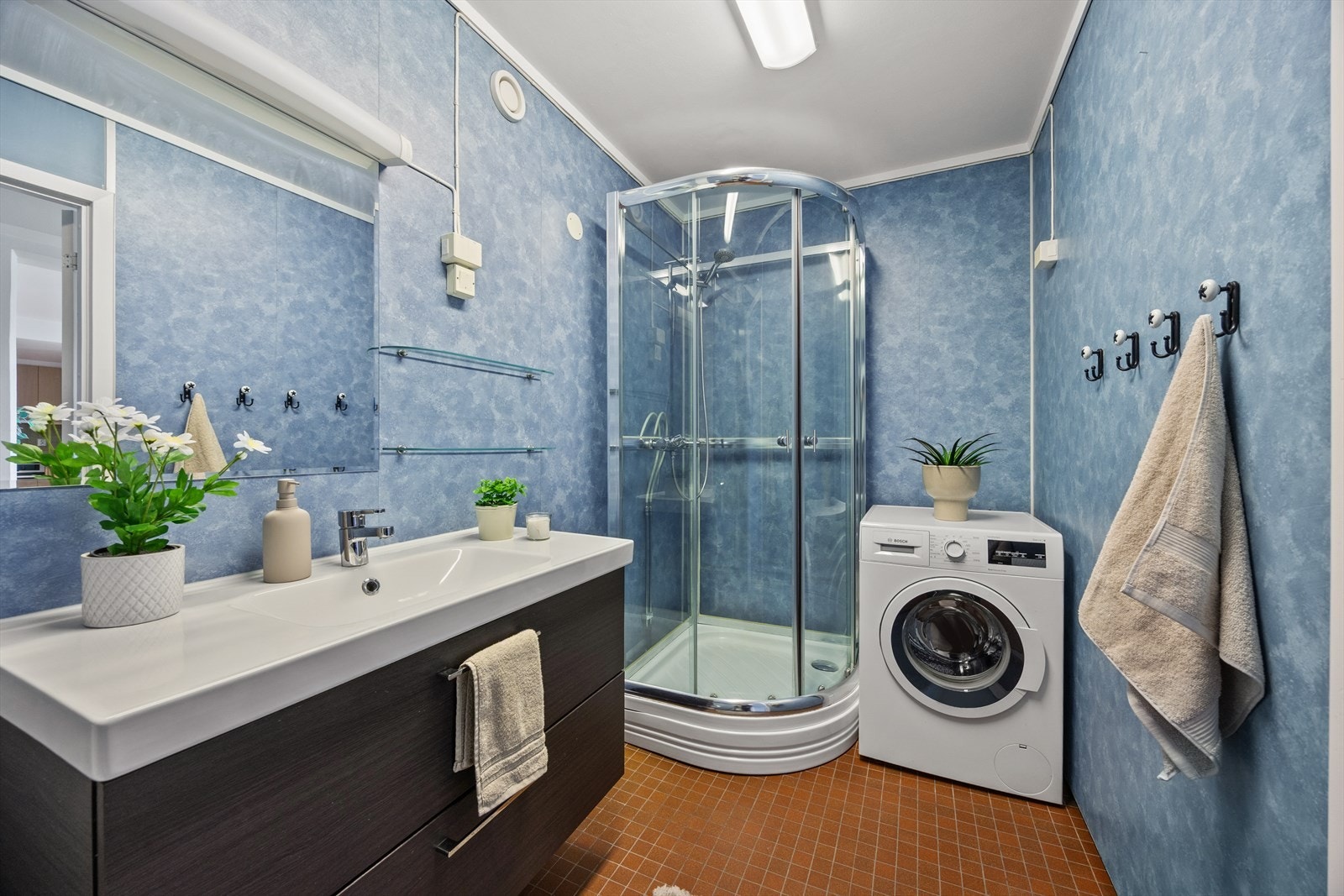Badet har flislagt gulv med varmekabler, vegger med våtromsplater og er innredet med servantmøbel og dusjkabinett. Galleribilde