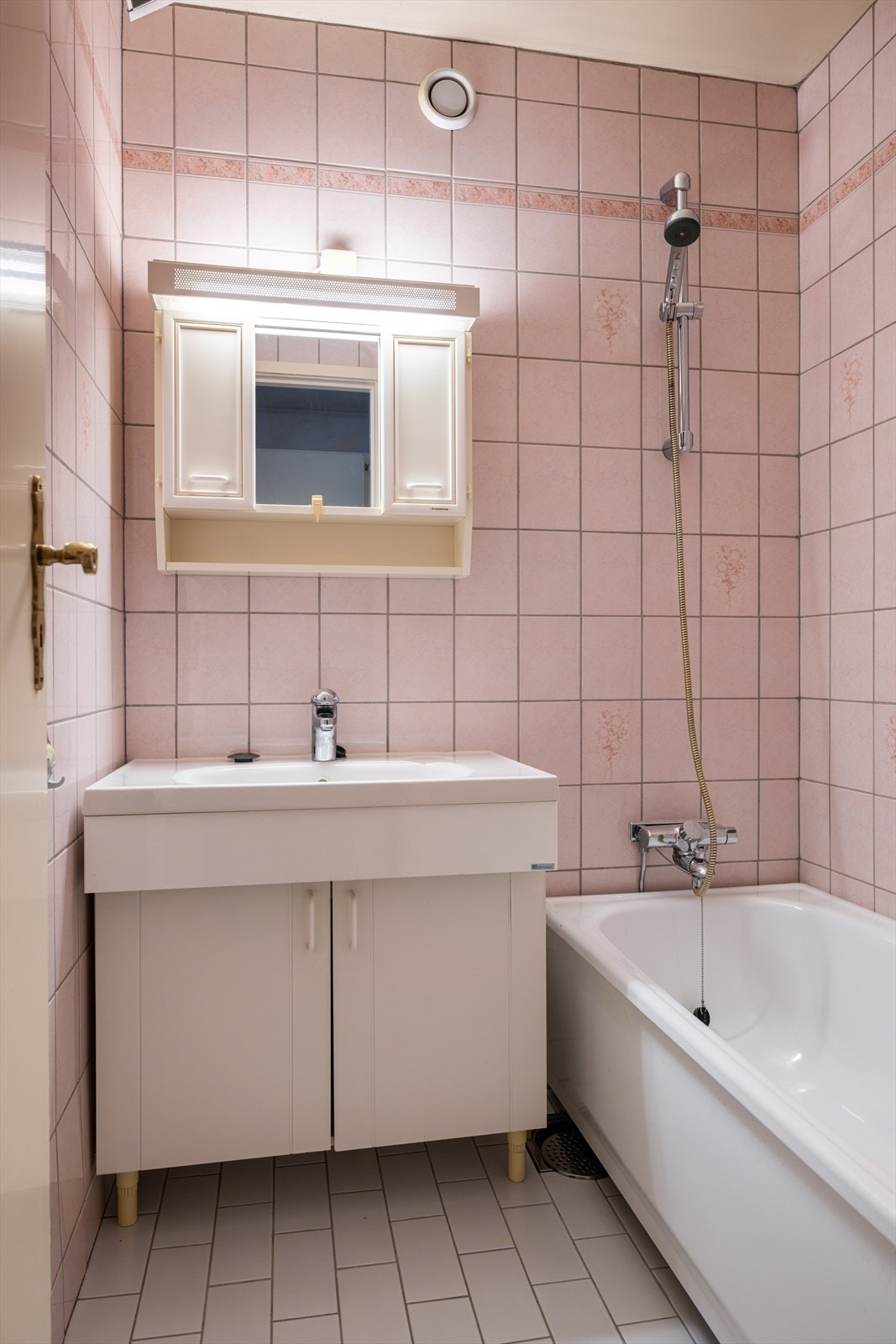 Eldre, flislagt bad med badekar, servantinnredning og speilskap. Galleribilde
