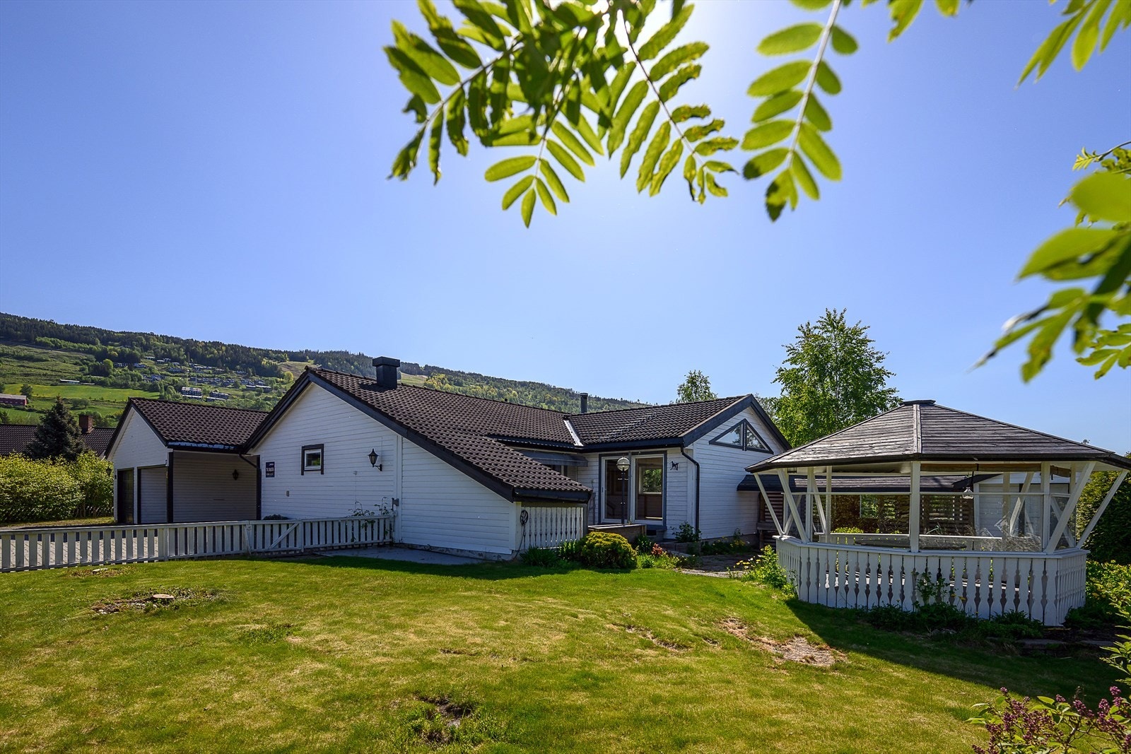 Uteområdet er pent opparbeidet med hellelagt uteplass, plen og en frittstående paviljong. Galleribilde