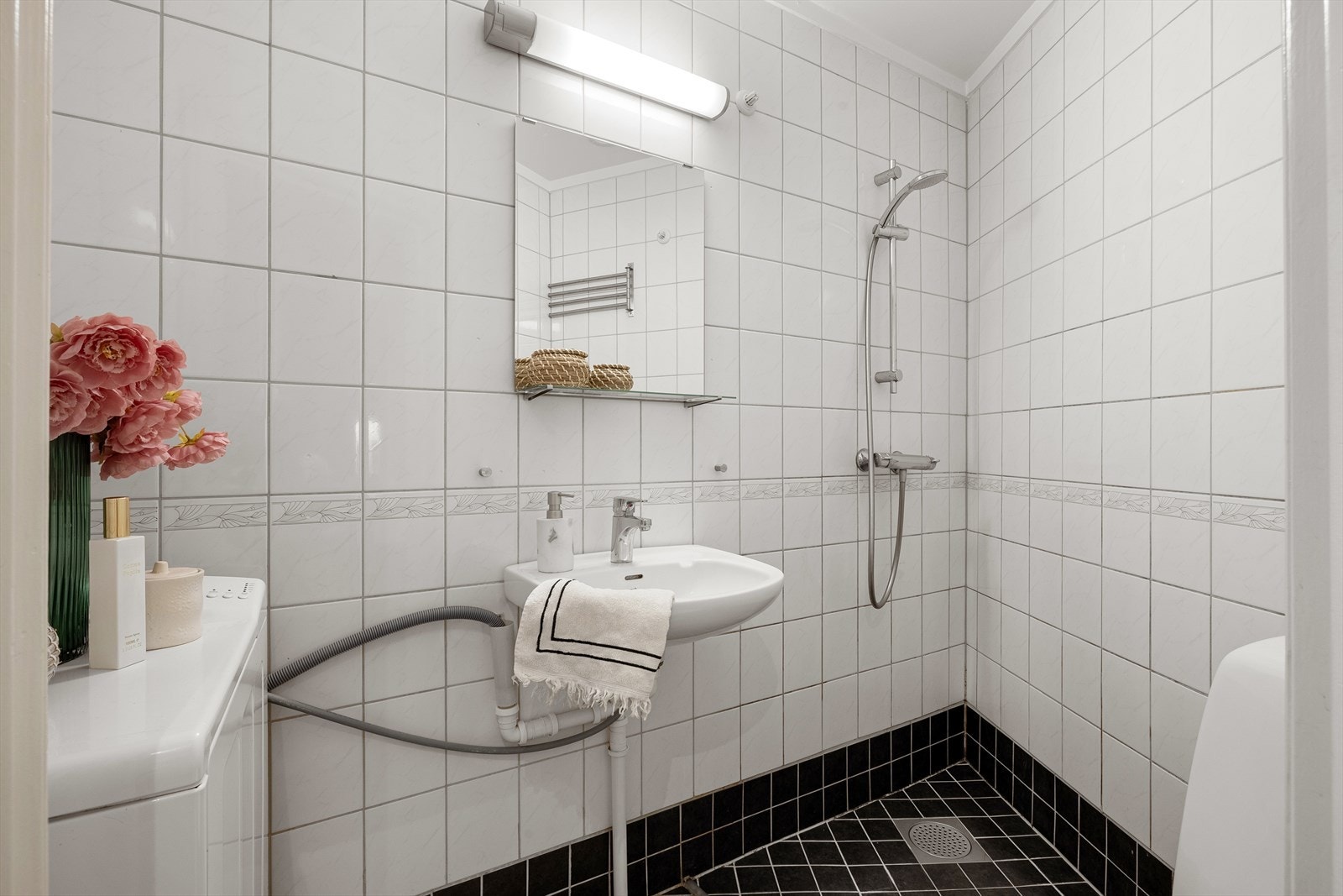 Flislagt bad med toalett, frittstående servant, uttak til vaskemaskin og dusjhjørne. Galleribilde