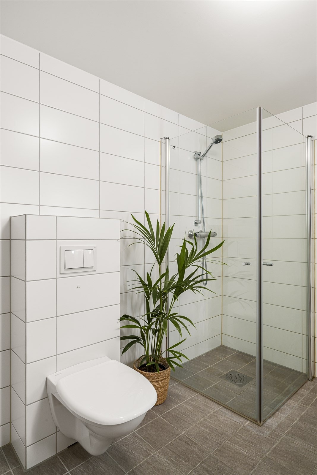 Badet er utstyrt med vegghengt toalett og et dusjhjørne med innfellbare glassdører. Galleribilde