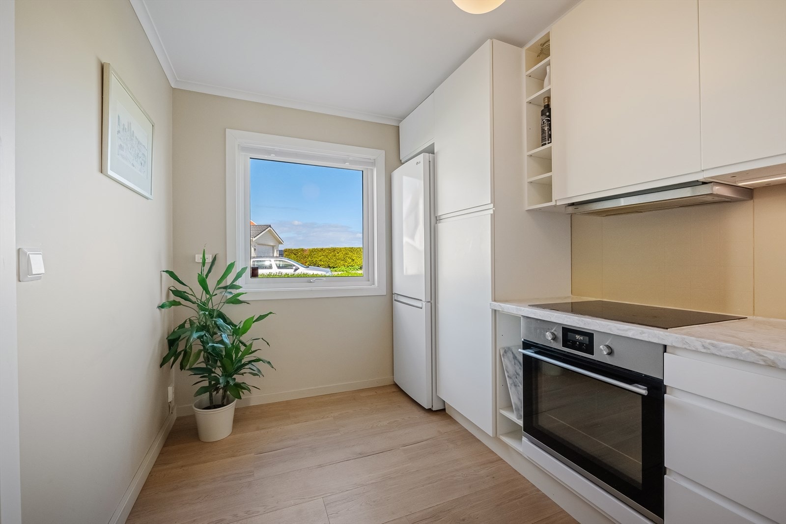 Innredningen har hvite, håndtaksløse fronter, soft-close funksjon og benkeplate med oppvaskkum i hjørnet. Galleribilde