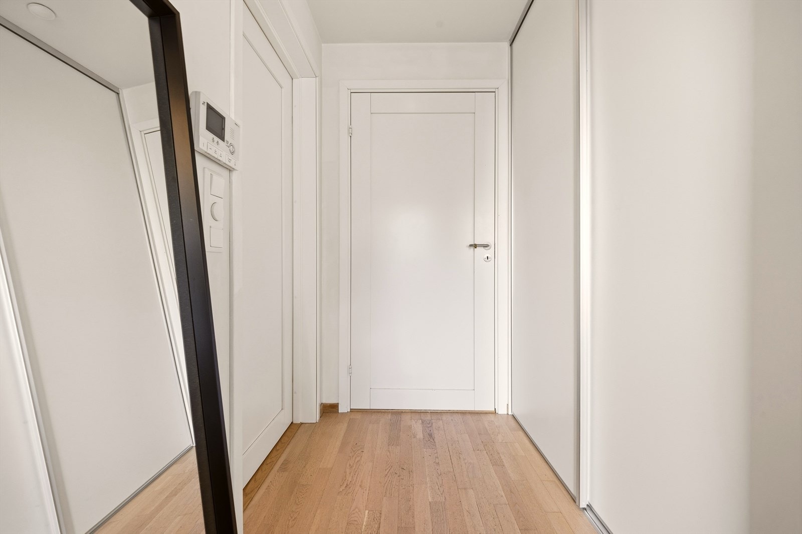 Inn ytterdøren ligger en innbydende entré med lyse overflater, downlightsbelysning og integrert skyvedørsgarderobe. Galleribilde