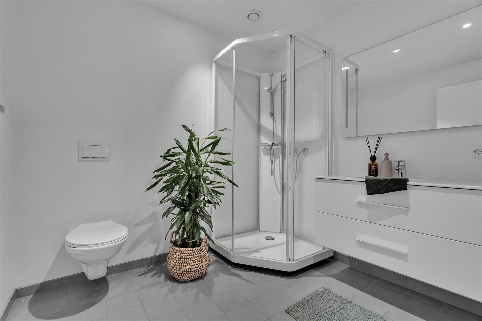 Badet er utstyrt med en moderne innredning som inkluderer nedfelt servant, vegghengt toalett og dusjkabinett. Gulvet er flislagt og har behagelig vannbåren varme, mens vegger og himling er kledd med malte plater. Galleribilde