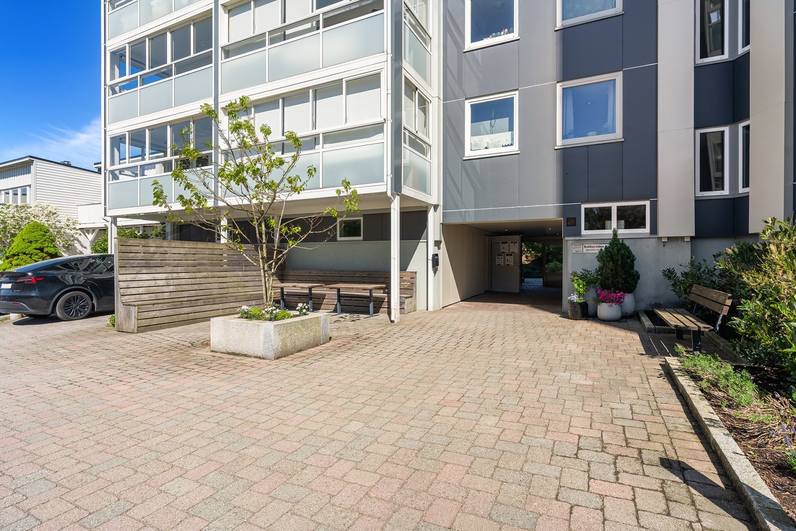 Ved inngangspartiet til boligblokken er det opparbeidet en hyggelig sitteplass. Det er forøvrig gjesterparkeringsplass her, samt mulighet for å lade el-bil mot betaling. Galleribilde