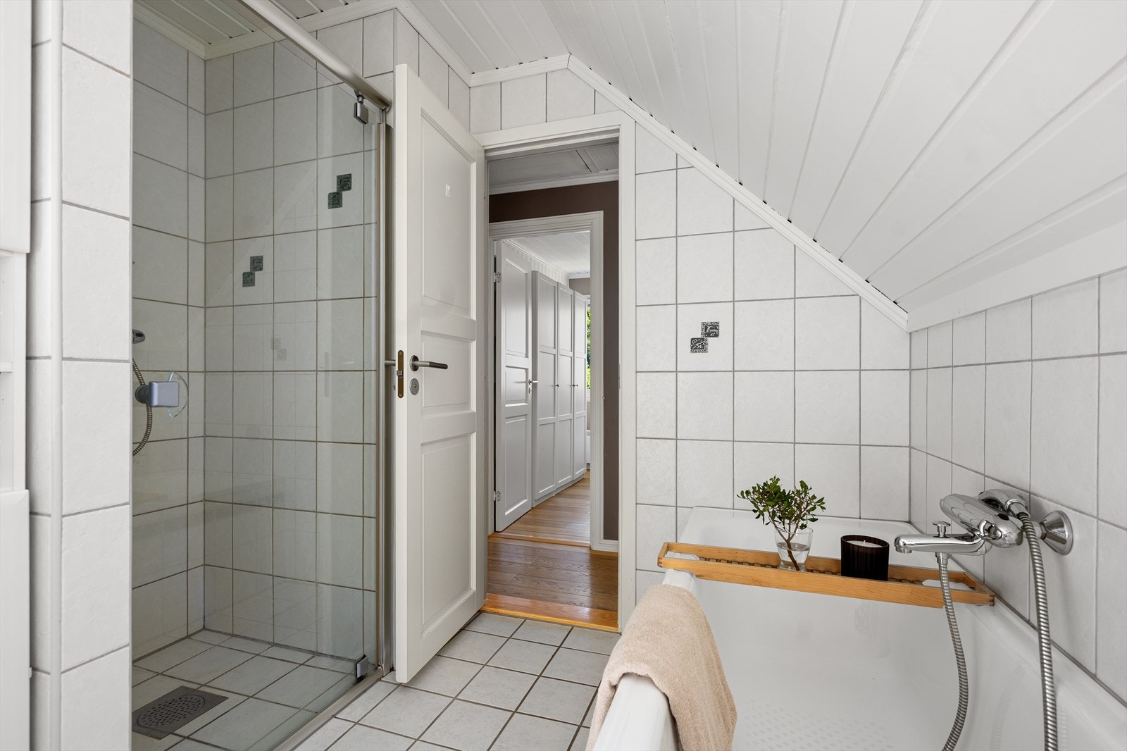 Badet er utstyrt med toalett, dusjnisje med glassdør og armatur fra FM Mattsson, samt innmurt badekar med håndholdt dusjhode. Deler av rommet ved kneveggen er byggemeldt som kott. Galleribilde