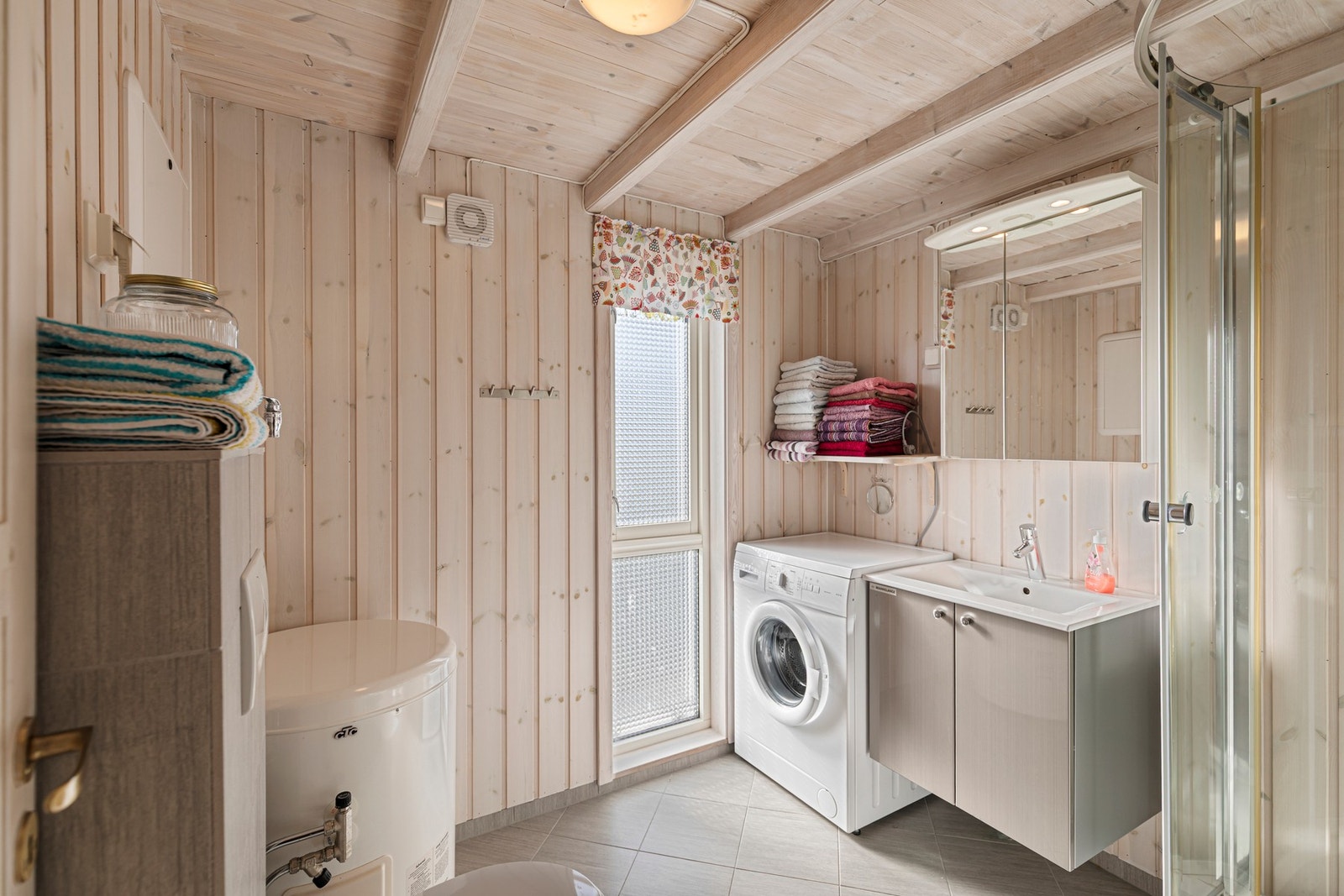 Badet er utstyrt med varmekabler i gulv, baderomsinnredning med servant, dusjkabinett og toalett. Det er opplegg for vaskemaskin på rommet. Galleribilde