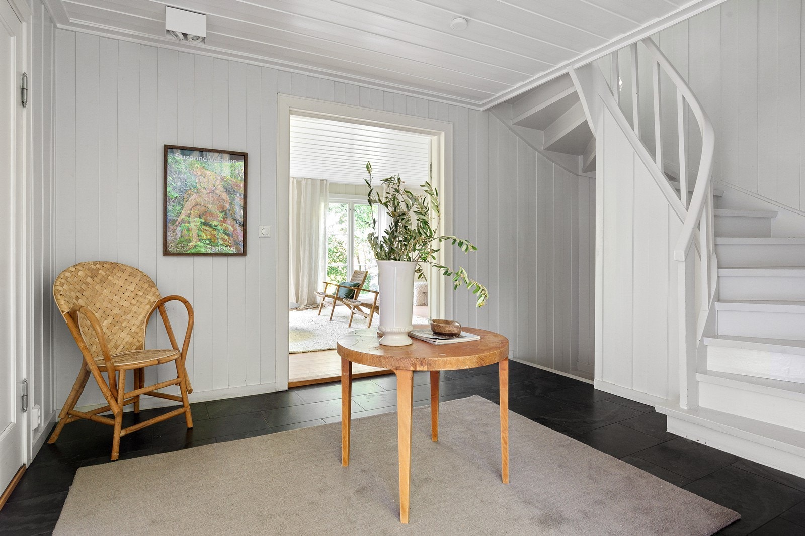 Hallen binder etasjene sammen med den originale, malte tretappen. Veggene har malt panel, som er gjennomgående i store deler av boligen. Galleribilde