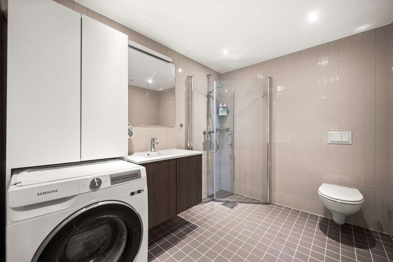 Flislagt bad fra 2022 med vannbåren gulvvarme. Badet har vegghengt toalett, dusjhjørne med glassvegger og opplegg for vaskemaskin. Galleribilde