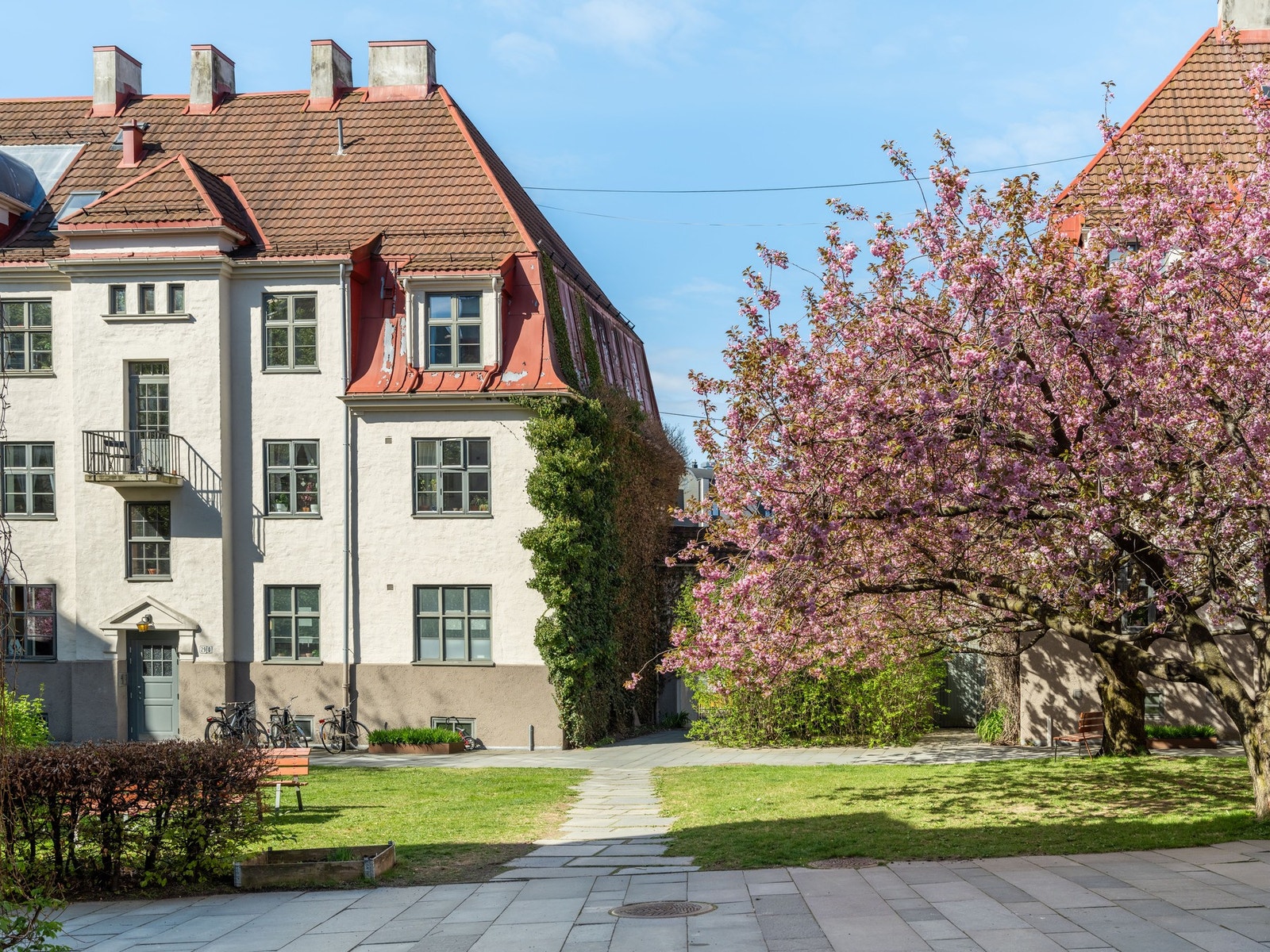 Bakgården er opparbeidet med busker, trær, sittegrupper, sykkelparkering og internveier belagt med belegningsstein. Galleribilde
