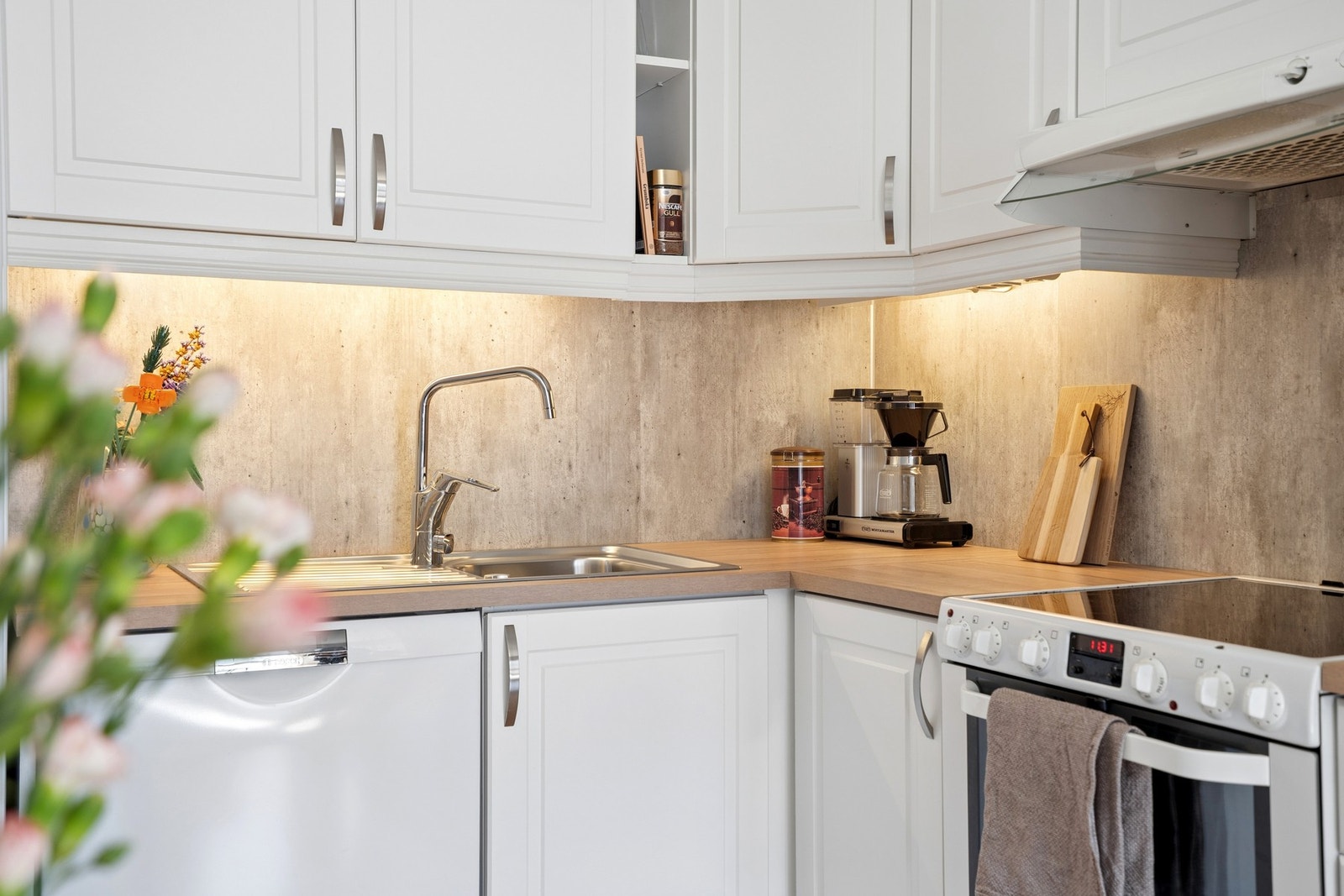 Kjøkkeninnredning med profilerte fronter og kitchenboard montert på vegg over benk. Galleribilde