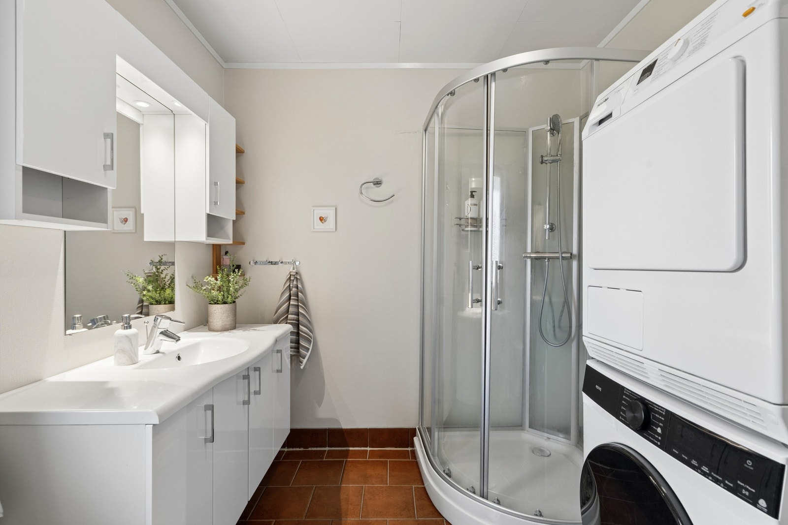 Badet har opplegg for vaskemaskin og tørketrommel, som gir en praktisk vaskeromsløsning. Galleribilde