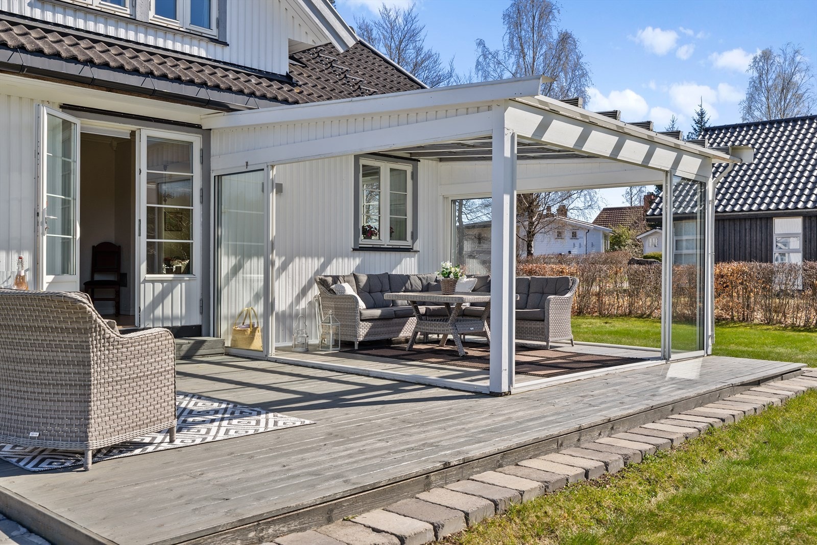 Romslig innglasset utestue med fleksible møbleringsmuligheter, enten som sofagruppe eller spisestue. Galleribilde