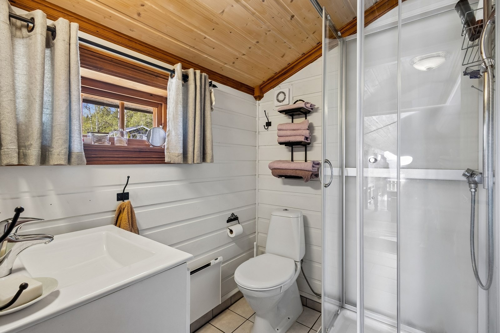 Badet har dusjkabinett, gulvmontert toalett og behagelig varme under det flislagte gulvet. Galleribilde