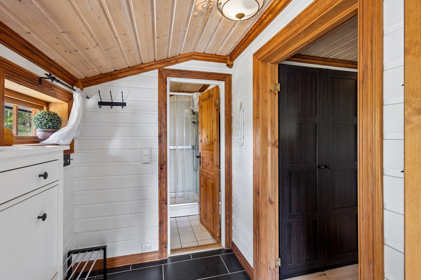 Entréen har lysmalte panelflater og koksgrå fliser på gulvet med lun varme under. Det er god plass til knaggrekke, skohylle og kommode. Galleribilde