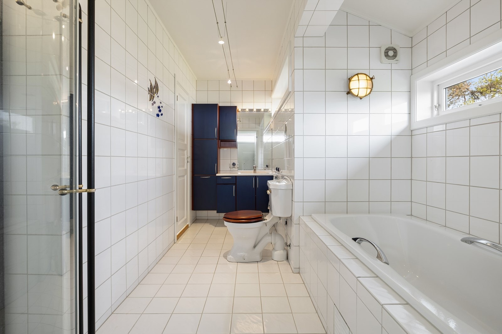 Det flislagte badet i 2. etasje er utstyrt med dusjnisje, badekar, innredning og gulvmontert toalett. Galleribilde