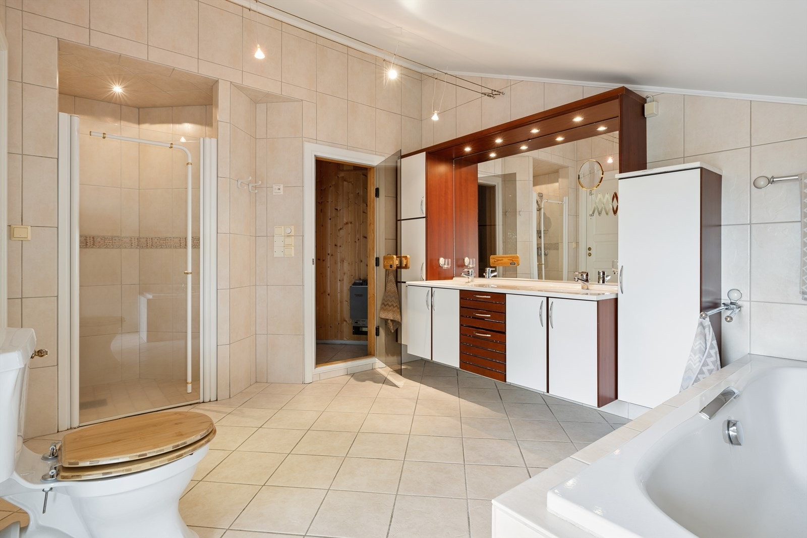 Badet er utstyrt med både dusjnisje, badekar, innredning med to servanter og gulvmontert toalett. Direkte adkomst til badstue. Galleribilde