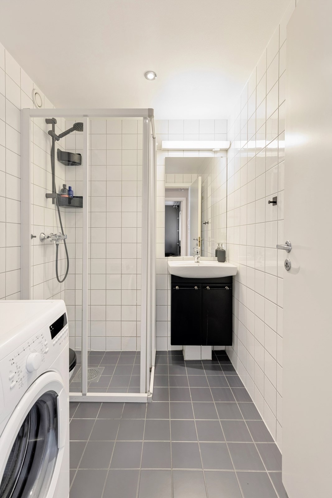Flislagt bad med opplegg for vaskemaskin og en funksjonell planløsning Galleribilde