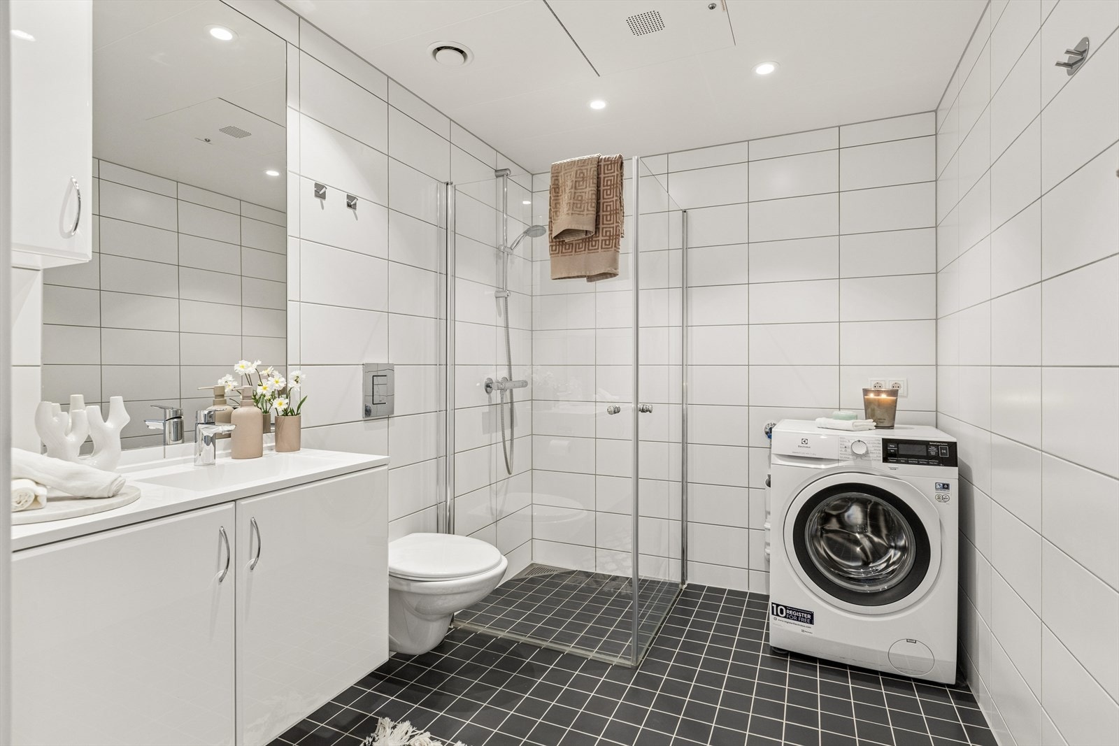 Flislagt bad med varmekabler i gulv og downlights i tak. Badet er på 5,1 kvm og har innfellbare dusjvegger. Opplegg for vaskemaskin Galleribilde